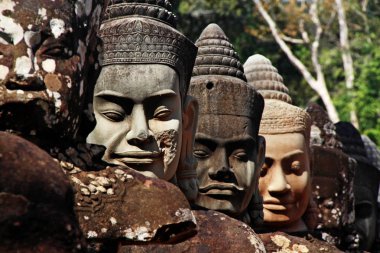 Efsanevi heykellerin sol tarafındaki efsanevi bir yılanın (Naga) başını çekerek Angkor Thom (Büyük Şehir), Siem Reap, Kamboçya 'nın güney kapısına giden hendeğin üzerinden geçiyorlar.