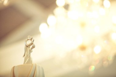 Gelin ve Damat düğün bebekleri arka planda avize ışık bokeh ile düğün pastası üzerine dekore