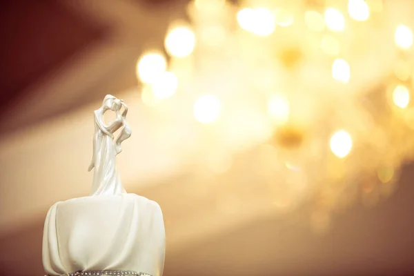 新娘和新郎婚礼娃娃装饰在婚礼蛋糕与吊灯在背景的散景 — 图库照片