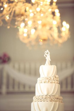 Gelin ve Damat düğün bebekleri arka planda vintage balkon ve avize ile düğün pastası üzerine dekore