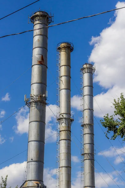 factory pipes against the blue sky with clouds