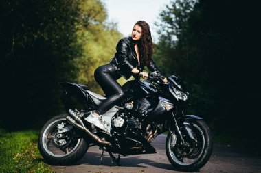 Motosikletli seksi kadın motosiklette oturuyor. Açık hava yaşam tarzı portresi