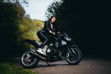 Motosikletli seksi kadın motosiklette oturuyor. Açık hava yaşam tarzı portresi