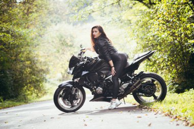 Motosikletli seksi kadın motosiklette oturuyor. Açık hava yaşam tarzı portresi