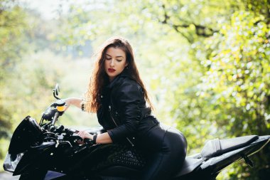 Motosikletli seksi kadın motosiklette oturuyor. Açık hava yaşam tarzı portresi