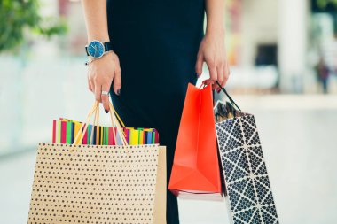 Alışveriş merkezinde alışveriş yapan siyah etekli kadın müşteriye yaklaş. İçinde alışveriş kağıtları olan kağıt torbaları taşıyan mutlu bir kadın. Satış ve indirim kavramı.