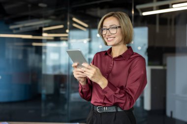 Dijital tablet gözlük takan mutlu iş kadını, çevrimiçi iletişimden zevk alıyor ya da modern ofis alanında uzaktan çalışıyor.