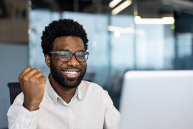 Gülümseyen Hintli genç bir kadın spor kıyafetiyle evde oturuyor cep telefonu ekranının önünde spor yapıyor, internetten yoga öğretiyor..