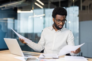 Masada oturan odaklanmış işadamı şık bir ofis ortamında profesyonel bir nişan için kulaklık kullanıyor. Görüntü üretkenliği, iletişimi ve profesyonelliği aktarır..