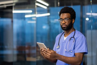 Gözlüklü ve kısa saçlı genç iş kadını kameraya doğrudan konuşuyor, el kol hareketleri yapıyor, modern ofis ortamında sanal bir toplantı sırasında bilgi veya eğitimi paylaşıyor.