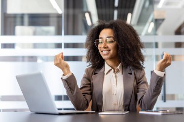 Gülümseyen Afro-Amerikan kadın, masada Lotus pozisyonunda oturuyor, gözleri kapalı meditasyon yapıyor ve dinleniyor..