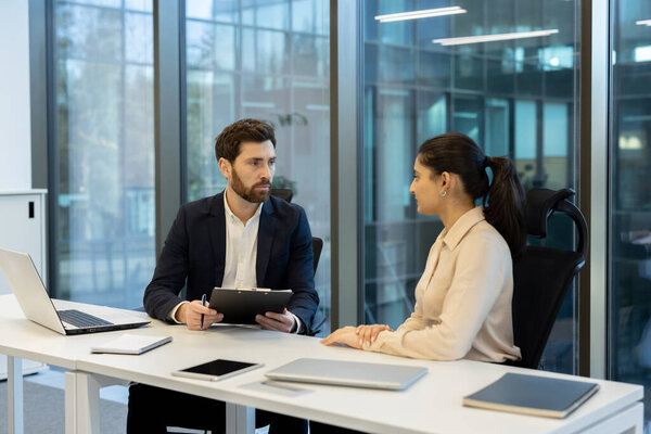Human resources manager conducting an important job interview with a female candidate in a contemporary corporate office, discussing potential employment and career opportunities