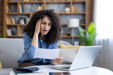 Kadın beklenmedik bir fatura karşısında şoke olmuş ve bunalmış durumda. Evde dizüstü bilgisayarından mali sıkıntılar ve bütçe sıkıntıları yaşıyor.