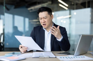 Kızgın genç Asyalı bir adam bir mektup ve kötü haber aldı. Ofiste hayal kırıklığına uğramış bir şekilde oturuyor ve elinde belgeleri tutuyor..