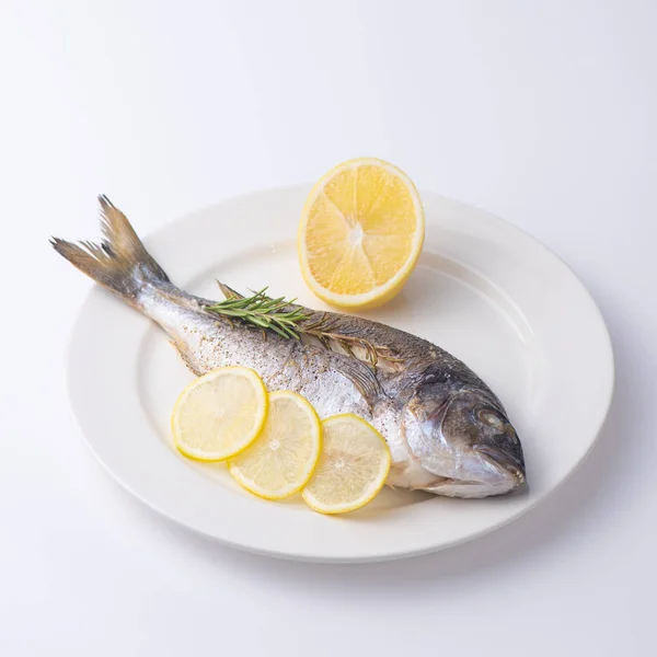 Dorada hal egy fehér tányérra citrommal. Elszigetelt. — Stock Fotó