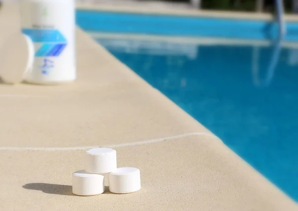 スイミングプールの消毒のためのサービスワーカーの手に白いミニ塩素タブレット 水泳シーズンの始まりは暑い夏です — ストック写真