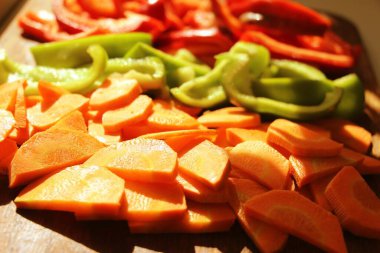 Tahta bir tahtada salata için dilimlenmiş çiğ havuç ve renkli dolma biber..