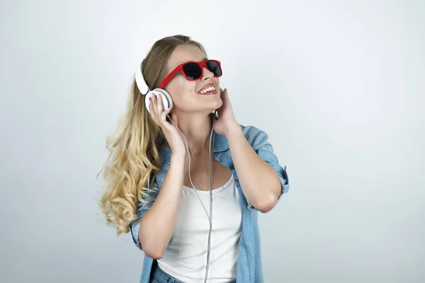 blond woman in headphones and sunglasses listening to music smiling white isolated background