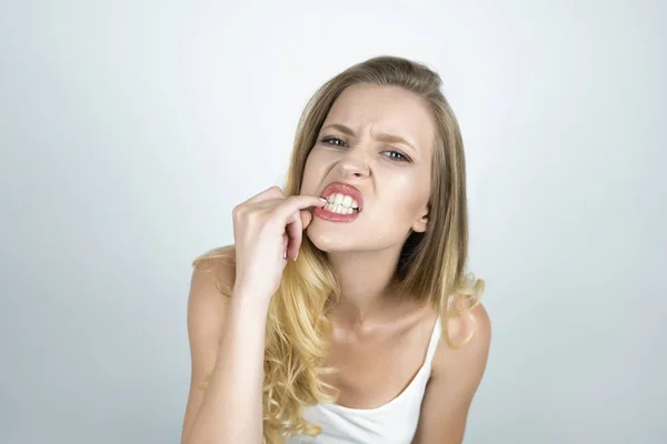 Rubia joven mujer que sufre dolor de muelas mostrando sus dientes con el dedo cerca de fondo blanco aislado — Foto de Stock