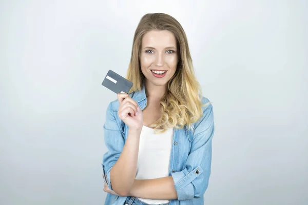 Rubia joven mujer sosteniendo tarjeta bancaria parece feliz aislado fondo blanco — Foto de Stock
