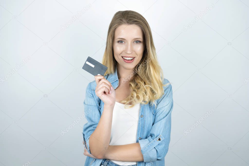 blond young woman holding bank card looks happy isolated white background