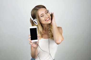 mutlu güzel genç kadın kulaklık akıllı telefon izole beyaz arka plan tutan müzik dinleme