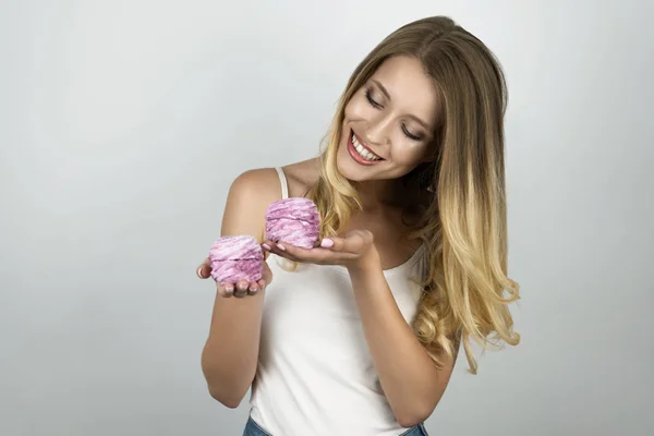 Mladá krásná blonďatá žena držící v obou rukách dortíky, izolované bílé pozadí — Stock fotografie
