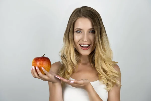 Úsměv blonďaté atraktivní ženy držící šťavnaté červené jablko v jedné ruce izolované bílé pozadí — Stock fotografie