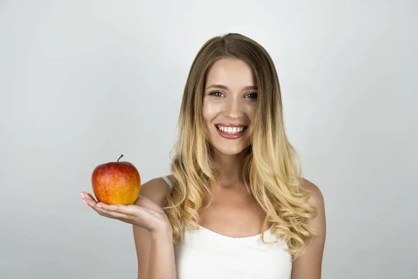 Úsměv blonďaté atraktivní ženy držící šťavnaté červené jablko v jedné ruce izolované bílé pozadí — Stock fotografie