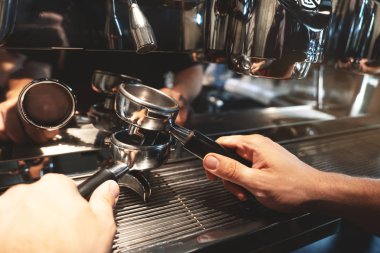 barista adam kahve makinesi arka plan üzerinde üstüst iki kahve tutucuları tutan yakın