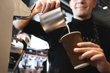 gülümseyen barista adam kafede profesyonel kahve makinesi önünde duran kahve ile kağıt fincan köpüklü sürahi gelen çırpılmış süt dökme