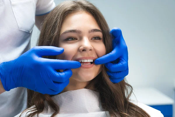 Krásná mladá brunetka, která vyšetřovala zubní úřad, zatímco zubař ukazoval výsledky bělení šťastným pacientům — Stock fotografie