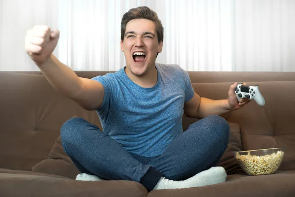 Joven hombre guapo completado con éxito la misión en el videojuego y se ve feliz y ganando —  Fotos de Stock