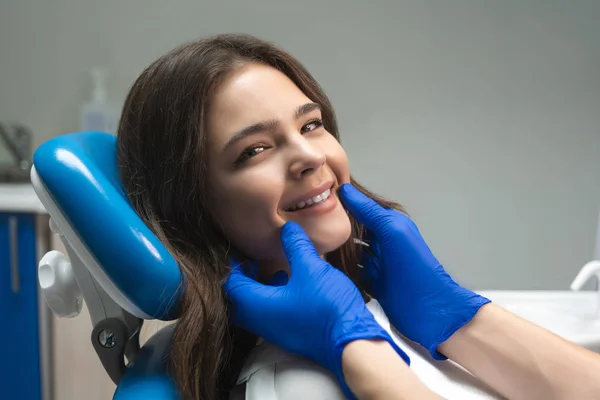 Satisfied with treatment result young beautiful woman patient looks happy sitting in dental chair in clinic — Stock Photo, Image