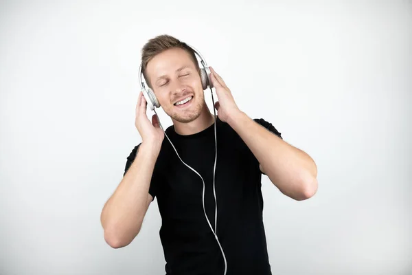 Joven guapo con camiseta negra escuchando música en auriculares que muestran un cartel aceptable sobre un fondo blanco aislado —  Fotos de Stock