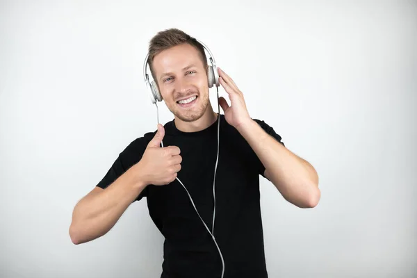 Joven guapo con camiseta negra escuchando música en auriculares que muestran un cartel aceptable sobre un fondo blanco aislado —  Fotos de Stock