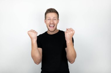 siyah t-shirt giyen yakışıklı genç adam kazanan başarı gösteren evet işareti olumlu gülen izole beyaz arka plan