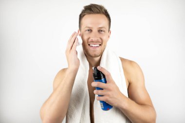 onun sabah rutin izole beyaz arka plan sırasında yüzüne tıraş köpüğü uygulayarak omuzlarında beyaz havlu ile genç adam görüntü