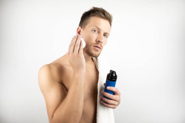 onun sabah rutin izole beyaz arka plan sırasında yüzüne tıraş köpüğü uygulayarak omzunda beyaz havlu ile genç adam görüntü