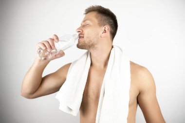 egzersiz beyaz izole arka plan sonra şişeden içme suyu omuzlarında beyaz havlu ile yakışıklı adam görüntü