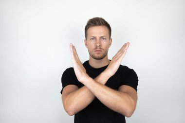 kollarını tutan siyah t-shirt giyen yakışıklı genç adam olumsuz ifade izole beyaz arka plan gösteren geçti