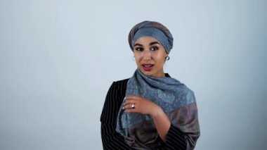 genç güzel arap kadın eliyle izole beyaz arka plan üzerinde hareket ile başörtüsü ayarlama gülümseyerek