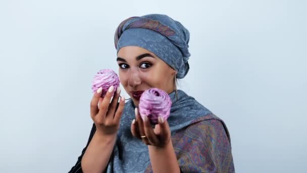 Joven hermosa mujer árabe sonriendo sosteniendo sabrosos cupcakes en estado de ánimo juguetón sobre fondo blanco aislado — Vídeo de stock