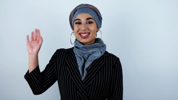 Jeune belle femme arabe agitant la main et souriant généreusement sur fond blanc isolé — Video