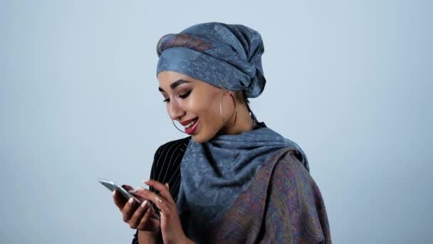 Young beautiful arabic woman reading something touching and pathetic in her smartphone on isolated white background — Stock Video