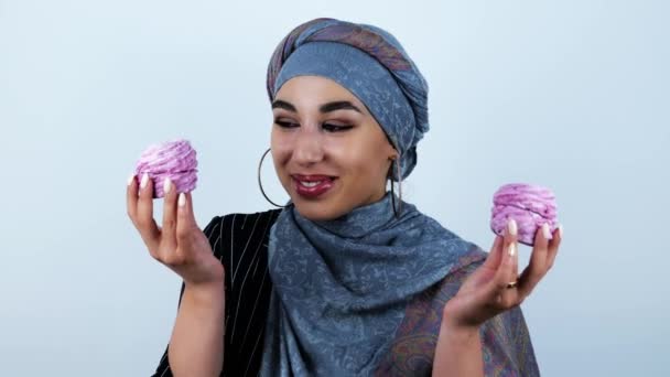 Joven hermosa mujer árabe sonriendo sosteniendo sabrosos cupcakes en ambas manos en aislado fondo blanco — Vídeo de stock