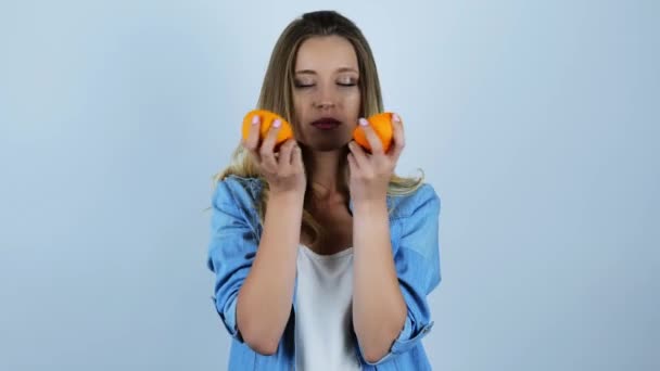 Joven hermosa mujer rubia sosteniendo dos mitades de naranja sobre fondo blanco aislado — Vídeos de Stock