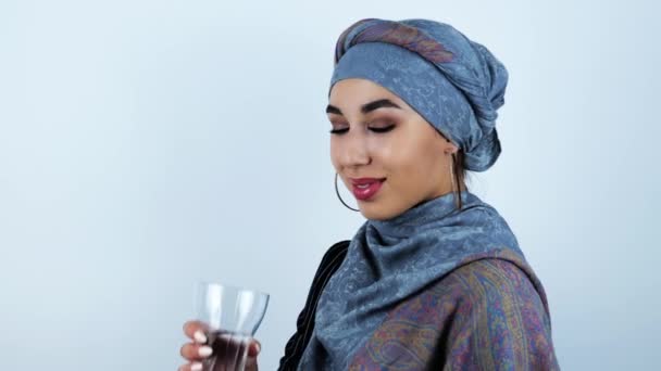 Νεαρή όμορφη αραβική γυναίκα πόσιμο νερό από το γυαλί σε απομονωμένο λευκό φόντο — Αρχείο Βίντεο