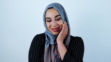 izole beyaz arka plan üzerinde eliyle yüzüne dokunarak biraz utangaç duygu gülümseyen genç güzel arap kadın