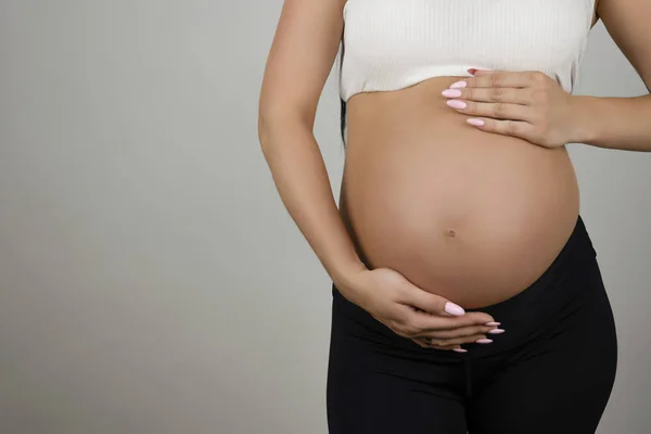 Donna incinta tenendo la pancia nuda con entrambe le mani su sfondo bianco isolato — Foto Stock